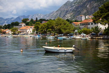 Fototapeta na wymiar Very beautiful embankment of the Bay of Kotor, a small fishing boat. Montenegro. A beautiful and cozy city, tiled houses. The concept of rest and vacation in Europe.