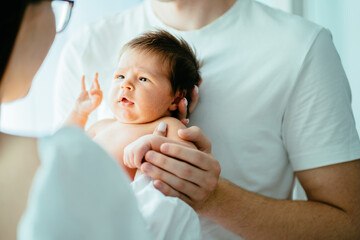 Obraz premium Unrecognizable parents with newborn baby girl. Close up portrait of two week old sweet new born baby attentively looking on her mother.