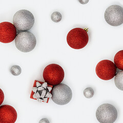 Christmas composition with silver and red christmas balls and gift box with surprise on white background. New Year holiday pattern