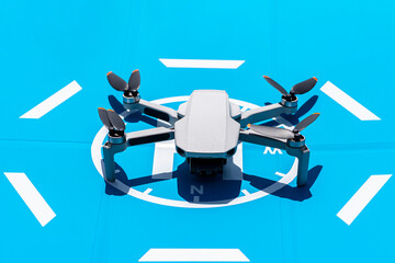 The drone is standing on a blue landing field, the plastic propellers are turned off and the camera...