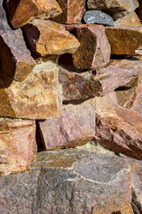 Background is made of natural stones of different colors and sizes. Natural texture. Brown granite. Vertical photo. Top view. Close-up.  Selective focus.