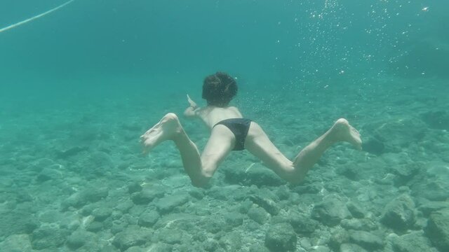 woman diving with a black bikini in pera pigadhi, greece