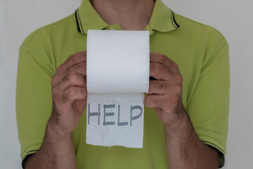 Help written on toilet paper roll in a man's hand. Concept of diarrhea and embarrassment