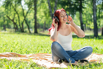 Young woman happens to have music in a summer park