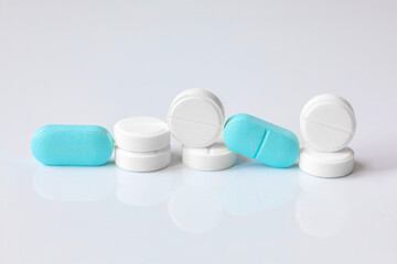Round white pills and oval blue tablets on a light background for the design of a pharmacy store....