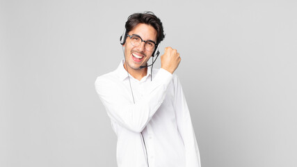 young hispanic man feeling happy and facing a challenge or celebrating. telemarketer concept