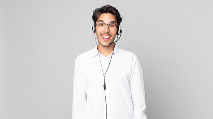 young hispanic man looking happy and pleasantly surprised. telemarketer concept