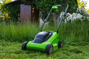Fototapeta na wymiar lawn mower on the grass, lawn care, mowing the grass, country cares, lawn mowing with an electric lawn mower