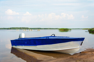 Aluminum blue fishing boat with a motor near the lake shore, fishing, tourism, active recreation, lifestyle. Background of nature. Natural landscape