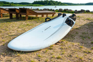 Surf board lies on the sand on the beach on the shore of the lake, sea, water sports, active lifestyle, vacation, heat, rest
