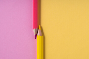 Pink and yellow pencils on pastel pink and yellow contrast background. education concept.top...