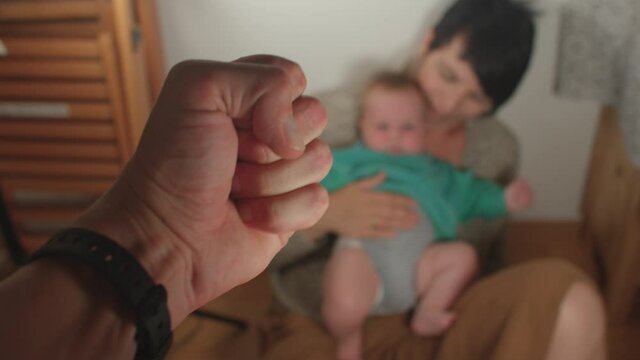 Close-up of a man's hand, clenching a fist. In the background, a mother and a child in fear. Domestic violence scene. The manifestation of aggression towards loved ones. Formation of fear.