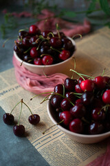 Ripe fresh cherry in two pink bowls on old paper background