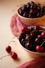 Ripe fresh cherry in two pink bowls on orange background
