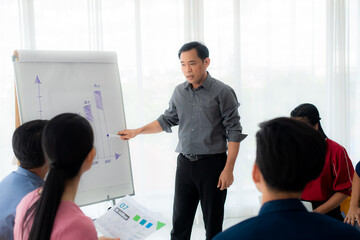 Asian male senior manager Teams are meeting and explaining information in flipcharts. and training for the team to work in meeting room.