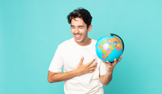 young hispanic man laughing out loud at some hilarious joke and holding a world globe map