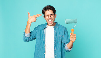 young hispanic man looking unhappy and stressed, suicide gesture making gun sign and holding a...