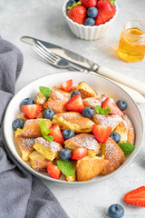 Kaiserschmarrn - traditional austrian pancake dessert with fresh berries and powdered sugar on a gray concrete background. Sweet breakfast. Copy space.