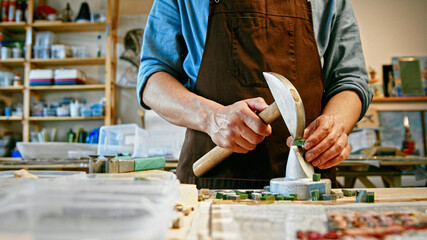 Young man with a hammer at work in studio