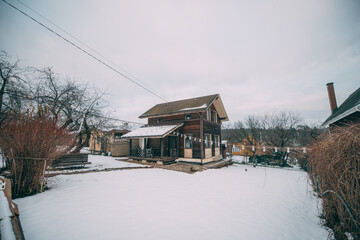 Two-storey wooden country house on a plot in winter. Outside view.