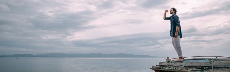 Fototapeta premium A lonely man walks along the beach on a cloudy day