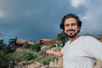Portrait of a male tourist on the beach on the background of Thai national houses
