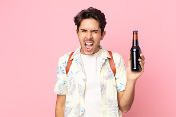young hispanic man shouting aggressively, looking very angry and holding a bottle of beer