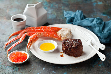 Carnivore-Ketogenic diet lunch or dinner. Filet mignon steak, butter sauce, crab legs and red caviar, selective focus. © Y. A. Photo