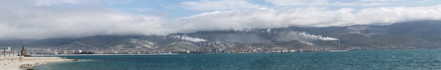 Panorama of the sea bay against the background of factories, ships, mountains and clouds