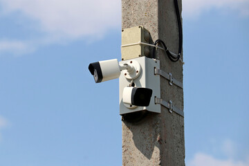 Outdoor surveillance video camera on a concrete pole in blue sky. Cctv camera, concept for...
