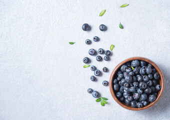 sweet fresh blueberries in a wooden  bowl  on a blue background. Top view and copy space