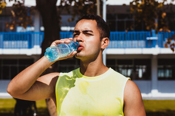 portrait of young latin man drinking a bottle of water after training in Mexico Latin America
