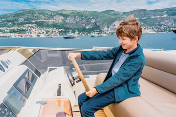 Captain boy drives the yacht. Travel adventure concept. Yachting with child on summer vacation....