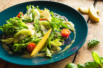 Ensalada saludable, baja en calorías con brotes verdes, tomate, mango, kiwi y vinagreta de mostaza. 