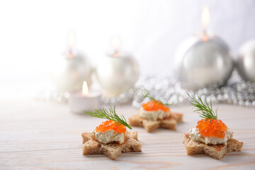 Holiday canapes from toasted bread in star shape, cream and red caviar with dill garnish on a light...