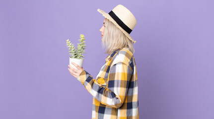 young pretty albino woman on profile view thinking, imagining or daydreaming and holding a...