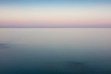 Minimalist image of sunrise at sea. First lights of the day of soft colors. Calm sea