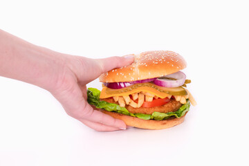 Hand grabbing a big chicken burger with cheese and vegetables
