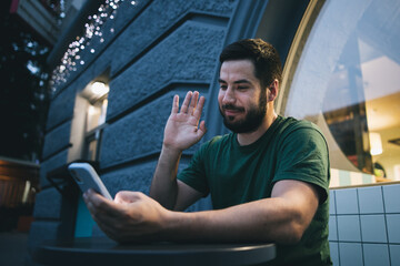 A young man looking at the mobile phone video call live stream outside