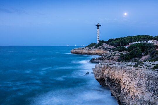 Torredembarra lighthouse at dusk. Image with blue tones of sky and sea. Mediterranean coast