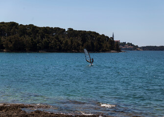 A man on a sailboat at sea,view from the beach