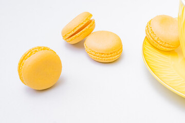 Yellow macaroons on a table with a yellow cup and saucer