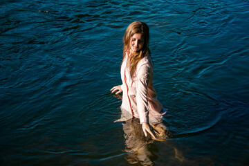 young woman bathes in the river enjoying the cool water