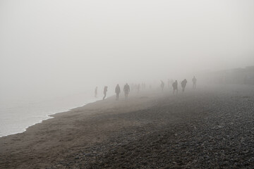 Shadowy figures in the fog on the beach