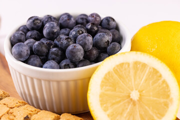 a bowl of blueberries and cut lemons on white close up