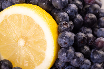 close up of a sliced lemon wedge against a pile of blueberries