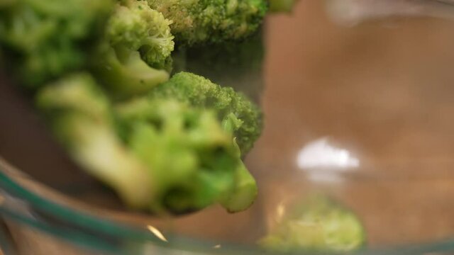 Skillet full of freshly cut broccoli cooking on the stove top - slow motion