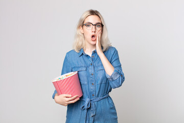 young pretty albino woman feeling shocked and scared with a pop corns bucket