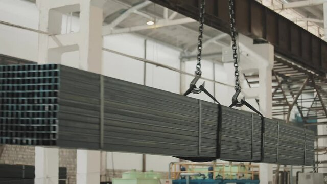 At the factory, a crane moves a bundle of packed pipes from one place to another. The pipes are very heavy. The crane copes with the task perfectly. Do not go under the pipes being moved.