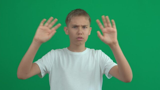 Denying, rejecting, disagree, disapproving. Teenage boy says no with crossed hands, stop gesture making negation sign over green screen choma key background